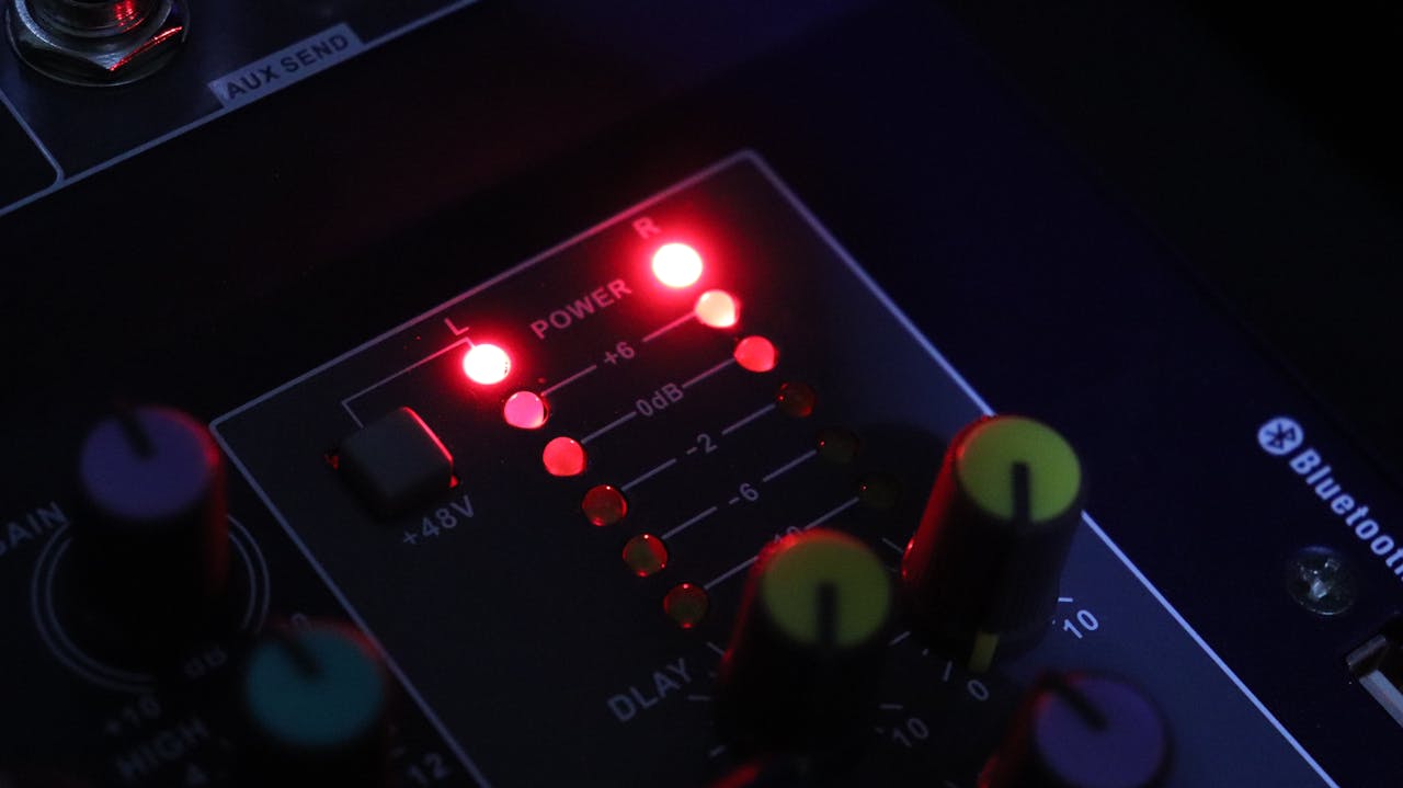 Detailed view of a lit audio mixer panel showcasing controls and indicators, perfect for tech themes.